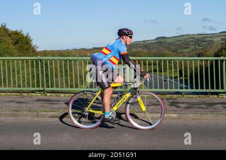 Ciclista maschile a cavallo di una Giant fibra di carbonio sport bici da strada sulla strada di campagna che attraversa il ponte autostradale nella rurale Lancashire, Regno Unito Foto Stock