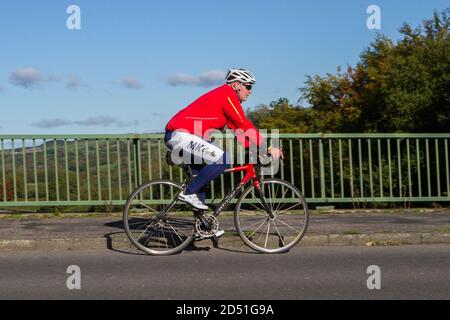 Ciclista maschile a cavallo di una Giant fibra di carbonio sport bici da strada sulla strada di campagna che attraversa il ponte autostradale nella rurale Lancashire, Regno Unito Foto Stock