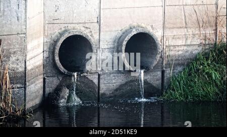 Grondaia. Deflusso d'acqua da una via di scarico (smaltimento dell'acqua, drenaggio delle tempeste), due tubi e acqua a flusso lento (deflusso diretto) dopo la pioggia Foto Stock