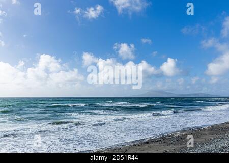 Onde che rotolano verso la riva in una giornata ventosa in Clew Bay con vista sull'isola di Clare dalla pietra spiaggia a Killadoon sul giro di Killeen passeggiate vicino Louis Foto Stock