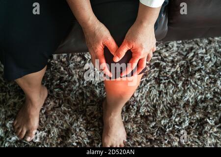Vecchia donna che soffrono di dolore al ginocchio a casa, il problema della salute concetto Foto Stock