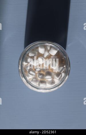 marshmallows in un vaso di vetro su sfondo azzurro Foto Stock