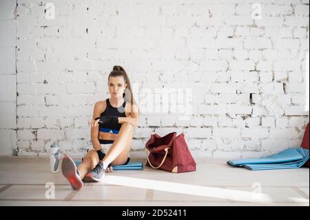 Una ragazza sta riposando dopo una sessione di addestramento individuale con un pugile professionista in una luminosa sala di allenamento Foto Stock