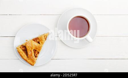 Pezzo di torta fatta in casa con mele e cannella e una tazza di tè su tavolo di legno bianco. Vista dall'alto. Foto Stock