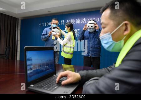 (201012) -- CHANGJI, 12 ottobre 2020 (Xinhua) -- gli addetti alla manutenzione hanno messo su apparecchiature VR per monitorare i lavori di manutenzione in loco presso una stazione di conversione nella prefettura autonoma di Hui a Changji, nella regione autonoma di Xinjiang Uygur, nel nord-ovest della Cina, 12 ottobre 2020. Una stazione di conversione su una linea di trasmissione a corrente continua ad altissima tensione che trasmette elettricità da Xinjiang ad Anhui, nella Cina orientale, ha iniziato la manutenzione lunedì. Durante la manutenzione di 13 giorni, verranno impiegate tecnologie 5G per garantire un flusso di lavoro fluido del progetto di trasmissione di energia elettrica. (Xinhua/Ding lei) Foto Stock