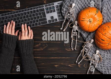 Mani femminili e decorazioni di Halloween con scheletro e laptop Foto Stock
