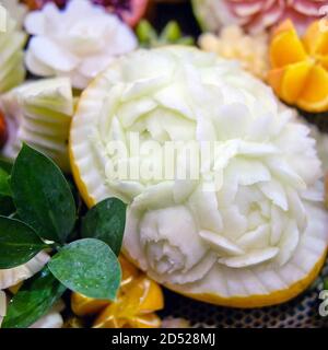 Decorazione della tavola fatta di verdure e frutta nella forma di fiori recisi su un melone Foto Stock