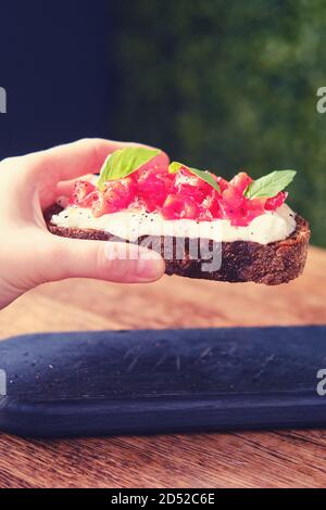 Porta la bruschetta a mano su un vassoio in un caffè, primo piano con uno spuntino italiano Foto Stock