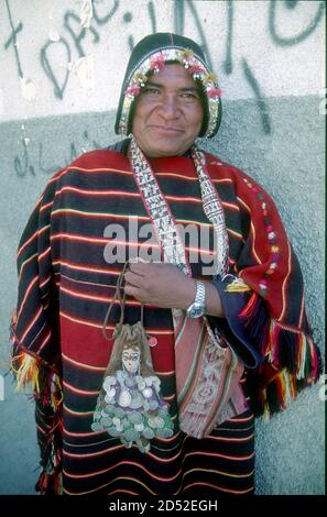 Questo venditore di tessuti indigeni di Tarabuco proviene da una località famosa per la sua tessitura. Il suo cappello in pelle imita un casco di conquistador, parlando volumi della conquista spagnola quasi 500 anni fa. La Paz, capitale della Bolivia. Foto Stock