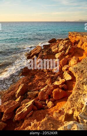 Rocce cadute di distacco costiero nei pressi della spiaggia di Cala Saona al tramonto con isolotto es Vedrá sullo sfondo (Formentera, Mar Mediterraneo, Spagna) Foto Stock