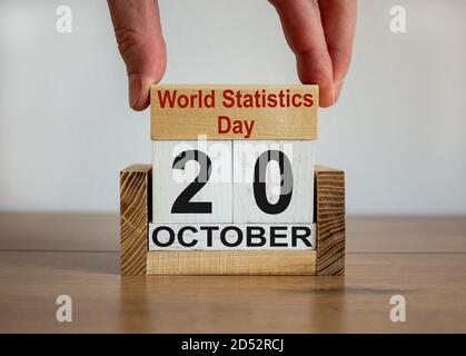 La mano maschile mette un blocco con l'iscrizione 'World Statistics Day' su cubi con la data di ottobre 20. Tavolo di legno. Bellissimo sfondo bianco, copia s. Foto Stock