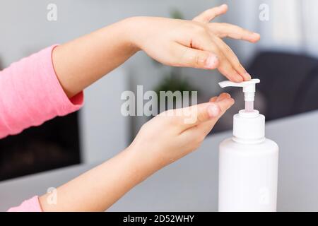 bambino che applica gel igienizzante sulle mani, protezione contro microbi e virus. Sapone liquido trasparente utilizzato per il lavaggio delle mani Foto Stock