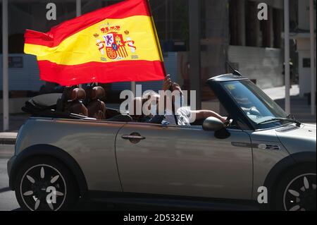 Un protester che indossa una maschera facciale è visto sventolare una bandiera spagnola all'interno di un veicolo come prende parte a una carovana durante la Giornata Nazionale Spagnola. Mentre la seconda ondata della pandemia del coronavirus colpisce la Spagna con alti livelli di infezioni, Il partito di estrema destra spagnolo VOX ha invitato gli spagnoli a manifestare contro il governo spagnolo in occasione della Giornata nazionale spagnola. Foto Stock