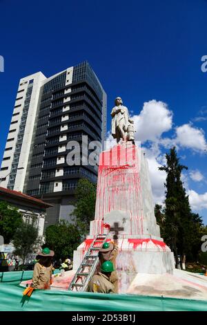 12 ottobre 2020, El Prado, la Paz, Bolivia. I lavoratori municipali puliscono un monumento a Cristoforo Colombo che è stato vandalizzato con vernice rossa in protesta contro il trattamento delle popolazioni indigene da parte dei colonizzatori europei. Oggi il 12 ottobre è il giorno di Colombo, festa nazionale in molti paesi delle Americhe che celebra l'anniversario dell'arrivo di Cristoforo Colombo nelle Americhe il 12 ottobre 1492. La data è diventata sempre più controversa; molti paesi hanno attenuato le celebrazioni o le hanno bloccate e gli attacchi ai monumenti a Colombo da parte di attivisti sono diventati sempre più comuni. Foto Stock