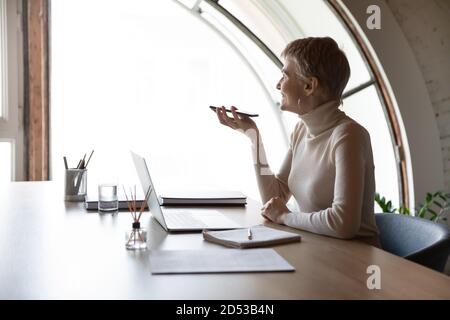 Donna d'affari sorridente parla sul cellulare utilizzando il vivavoce Foto Stock