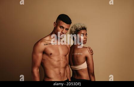 Fit african american coppia in piedi insieme sostenere il movimento nero Lives materia. L'uomo con le parole vite nere la materia scritta sul petto in piedi Foto Stock