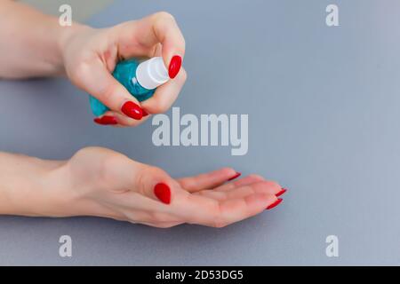 Donna premere sul dispenser e strizzare il gel di sapone morbido sul palmo, colpo di closeup su fondo piatto. Sapone liquido trasparente utilizzato per il lavaggio delle mani Foto Stock