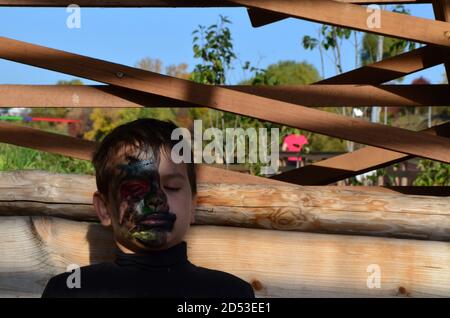 ragazzo con trucco nero per halloween, zombie. Spaventoso ragazzo sorridente che indossa il trucco del cranio per Halloween Foto Stock