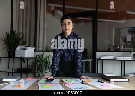 Ritratto di giovane donna d'affari indiana fiduciosa che posa in carica Foto Stock