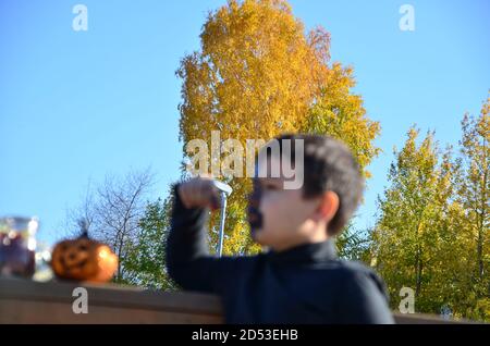 ragazzo con trucco nero per halloween, zombie. Spaventoso ragazzo sorridente indossando il trucco del cranio per Halloween lanterna di zucca, dolci Foto Stock