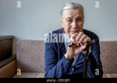 Mani di una vecchia donna appoggiate su una canna. Vecchiaia, solitudine, problemi di memoria. Foto Stock