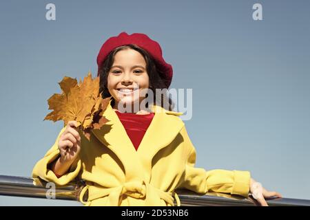 Idee per il tempo libero d'autunno. Bambina adorare la stagione autunnale. Kid tenere foglie di acero. Piccola ragazza indossare abbigliamento cadere all'esterno. Autunno lista della benna per bambini. Cielo chiaro e di buon tempo. Ispirando caduta. Foto Stock