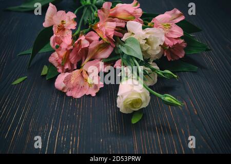 Bouquet di gigli inca rosa su fondo di legno nero Foto Stock