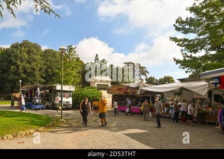 Vista del mercato settimanale nei Giardini di Lizza a Siena con bancarelle, gente e la statua di Giuseppe Garibaldi in estate, Toscana, Italia Foto Stock