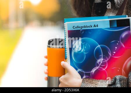 Primo piano di una studentessa di teen woman con notebook, caffè in movimento, zaino pronto per l'esame di prova con pausa caffè nel campus universitario. Ritorno a scuola. Univ Foto Stock