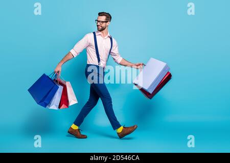 Foto di profilo a lunghezza intera di bell'uomo d'affari portare molti borse acquistare roba di vacanza centro commerciale buon umore indossare specifiche pantaloni per magliette sospendenti Foto Stock