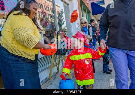 Una donna passa la caramella come un trick-or-treater vestito come un pompiere guarda nella sua ciotola, 31 ottobre 2011, a Columbus, Mississippi. Foto Stock