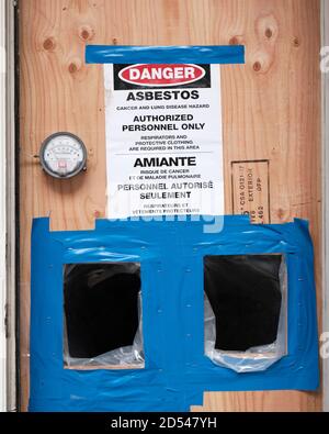 Cartello pericolo amianto all'ingresso della porta del cantiere, salito con legno compensato. Ottawa, Canada. 8 ottobre 2020. Foto Stock
