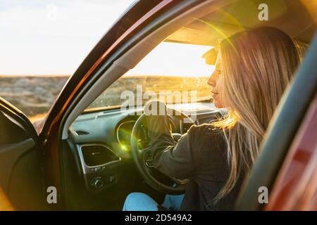 Donna che guida fuori strada per catturare il tramonto paese Foto Stock