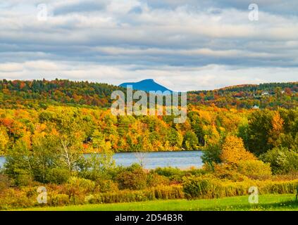 Lago Iroquois circondato da foreste in colori brillanti autunno fogliame Con Camel's Hump Mountain in lontananza Foto Stock