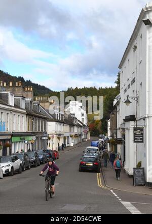 Un ciclista viaggia lungo la strada principale di Dunkeld, Perthshire, Scozia, Regno Unito, Europa Foto Stock