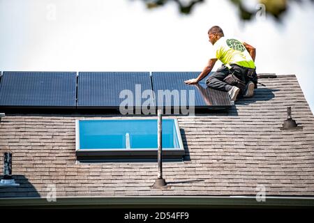 Herndon, Stati Uniti d'America - 27 agosto 2020: Operaio dell'uomo della persona che installa i pannelli solari del tetto montati sulle scaffalature e sulle rotaie sulla parte superiore della casa residenziale Foto Stock