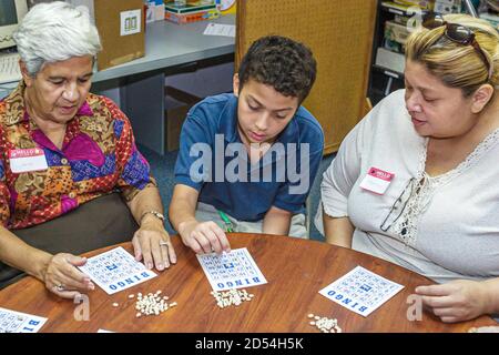 Miami Florida,giorno intergenerazionale delle guarnizioni di Pasqua,anziano anziano anziano donna donne ispaniche,ragazzo visite volontarie visitare plays giocare a bingo, Foto Stock