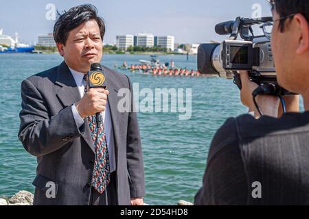 Miami Florida,Bayfront Park Hong Kong Dragon Boat Race Festival,uomo asiatico maschile media reporter segnalazione TV trasmissione, microfono cameraman s. Foto Stock