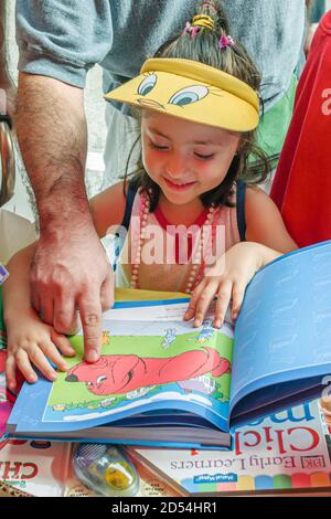 Miami Florida,Dade College Campus,International Book Fair vendor stall seller books,man father girl child looking reading children's book, Foto Stock