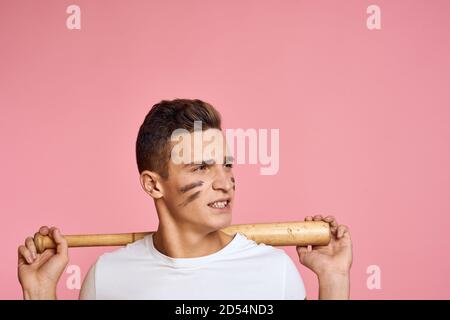 Uomo energico con un pipistrello su una T-shirt di sfondo rosa modello di aggressività delle linee nere di make-up del volto Foto Stock