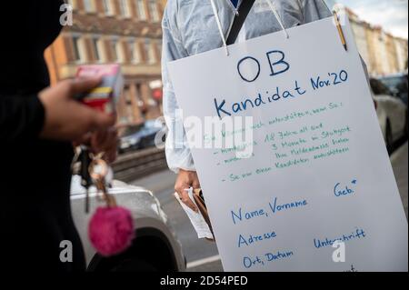 12 ottobre 2020, Baden-Wuerttemberg, Stoccarda: Christian Horn è in piedi nel centro della città con un segno che dice 'candidato OB Nov 20' e i requisiti per la firma a sostegno di un candidato, e sta parlando con i passanti. Poco prima della fine del periodo di candidatura per i candidati alle elezioni mayoral svoltesi a Stoccarda l'8 novembre, cerca di raccogliere le ultime firme di sostegno per se stesso. Il termine è scaduto il 12 ottobre 2020 alle ore 18.00. Il 13 ottobre, il comitato elettorale comunale deciderà quali candidati saranno ammessi alle elezioni. Foto: Sebastian Gollnow/dpa Foto Stock