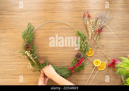 Carina donna decora la corona dell'avvento con le mani Foto Stock