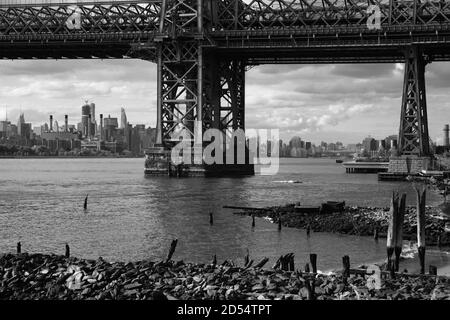 Vista di Manhattan attraverso l'East River sotto il Williamsburg Bridge che collega Brooklyn a Manhattan. Monotono, foto in bianco e nero. New York Foto Stock