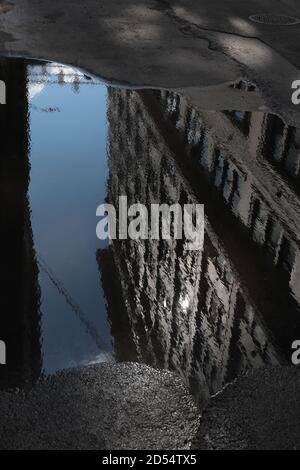 Riflessione gigante in puddle lungo Plymouth Street a DUMBO, Brooklyn, verso i ponti di Manhattan e Brooklyn. Strada deserta. Monocromatico, a toni. WA Foto Stock