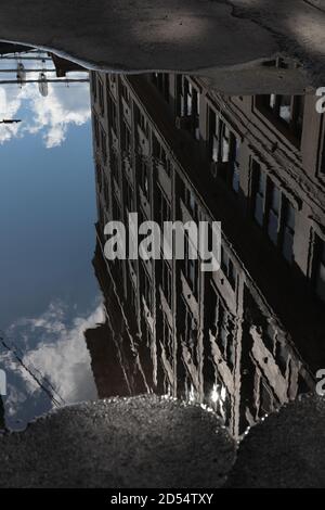 Riflessione gigante in puddle lungo Plymouth Street a DUMBO, Brooklyn, verso i ponti di Manhattan e Brooklyn. Strada deserta. Foto Stock