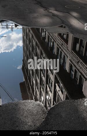 Riflessione gigante in puddle lungo Plymouth Street a DUMBO, Brooklyn, verso i ponti di Manhattan e Brooklyn. Strada deserta. Foto Stock