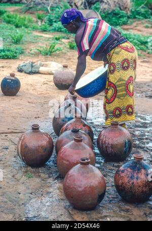 DaN Gaya, Niger. Le pot d'acqua delle donne si sono allineate al pozzo per riempire. Fotografato luglio 1998. Foto Stock