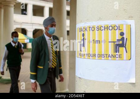 Nairobi, Kenya. 12 Ott 2020. Forma 4 gli studenti della scuola secondaria di Jamhuri camminano oltre un poster di consapevolezza del coronavirus mentre indossano i facemasks il loro primo giorno nella scuola. Il governo keniano ha riaperto le scuole essendo stato chiuso da marzo a causa della pandemia del Covid-19. Gli studenti di grado 4, classe 8 e forma 4 sono stati ammessi di nuovo in classe nell'ambito della graduale riapertura delle scuole. È obbligatorio seguire le misure preventive del Covid-19, come ad esempio indossare maschere facciali, prendere le mani e lavarsi le mani mentre si trovano nei locali della scuola. Credit: SOPA Images Limited/Alamy Live News Foto Stock