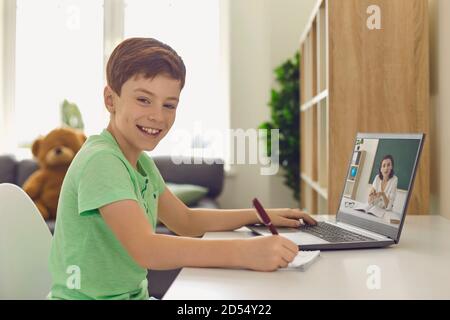 Ragazzo sorridente che studia a casa tramite un computer portatile Foto Stock