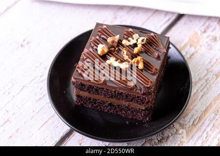 torte di cioccolato brownies dolci dessert su piastra di ceramica nera con guarnizione dadi Foto Stock